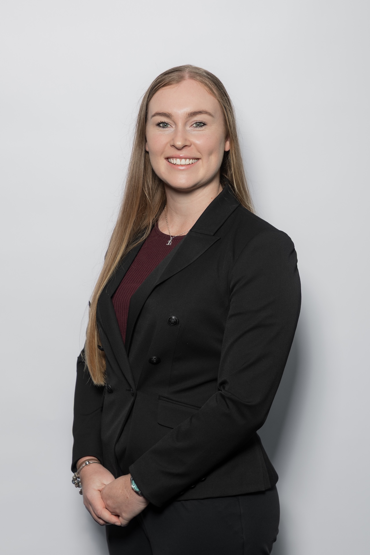 Charlotte Sly, legal professional at Croy Legal, in a black blazer, smiling against a light grey background.